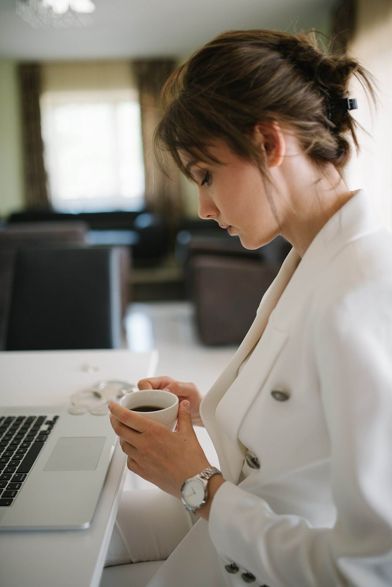 Wanita profesional membaca ketentuan di layar laptop sambil menikmati kopi