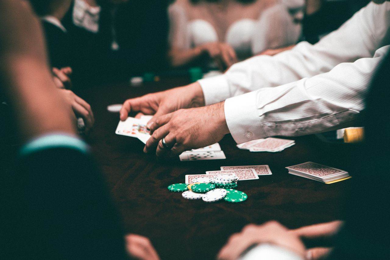 Pemain terkonsentrasi di sekitar meja poker saat kartu dibagikan